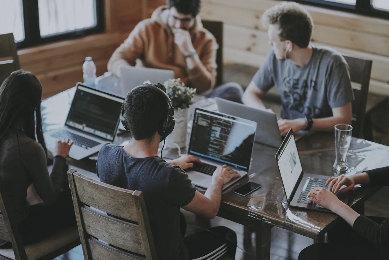 Une équipe travaille sur ses ordinateurs portables autour d'une table.